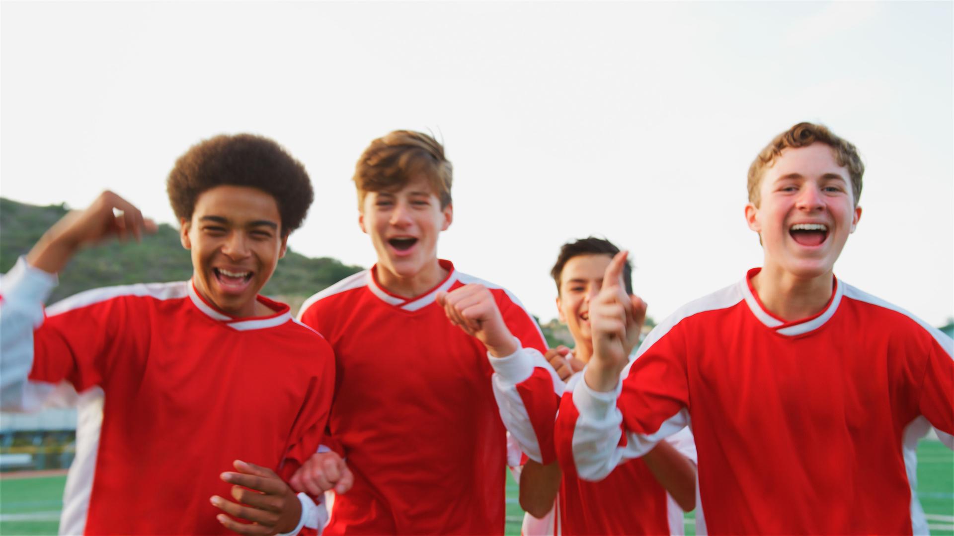 Portrait Of Multi-Cultural Male High School Soccer Team Celebrating Looking Into Camera