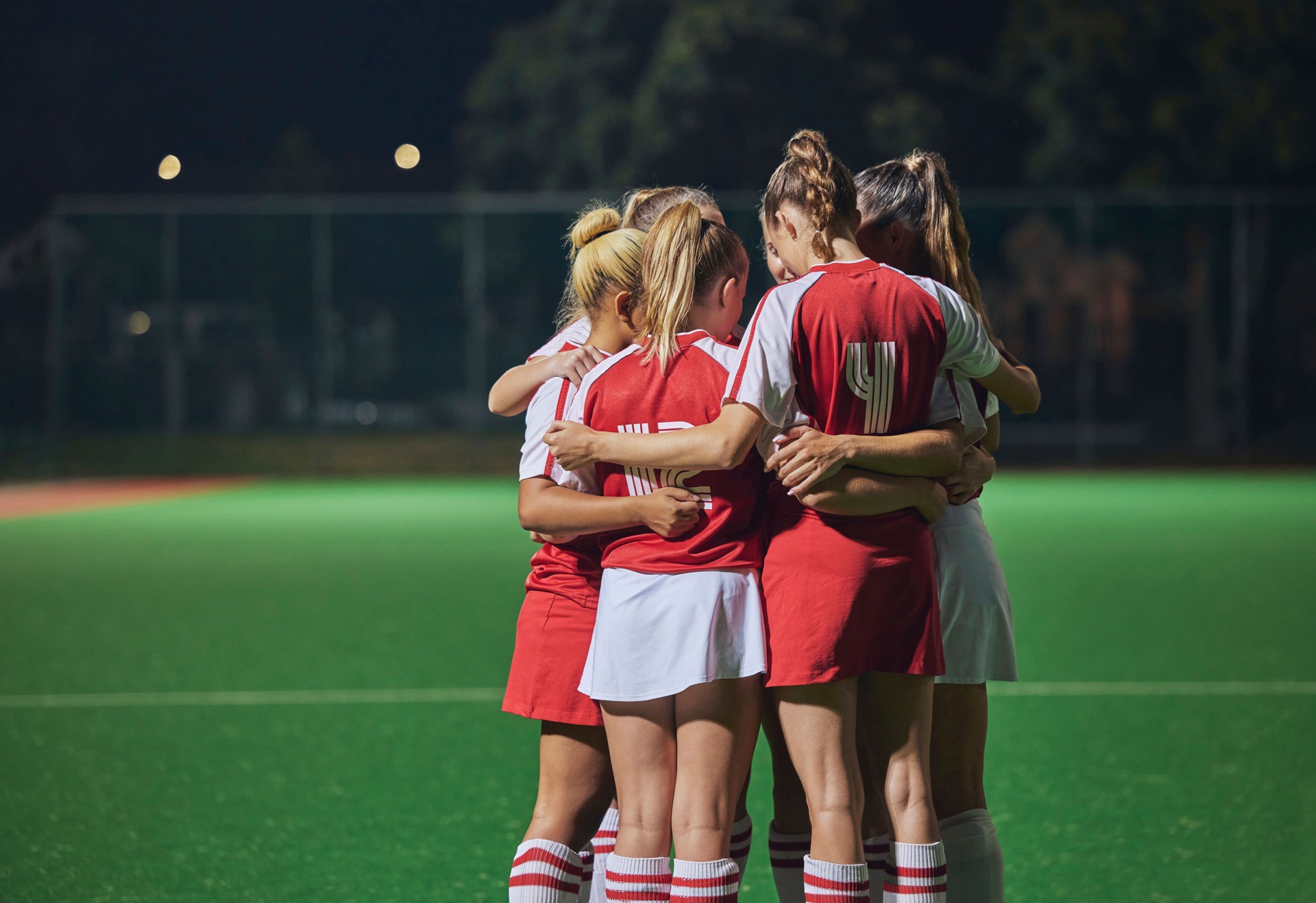 Huddle, soccer teamwork or football women on soccer field or stadium at night for support, motivation or workout game. Fitness, wellness or sports health trust, game partnership or planning on field